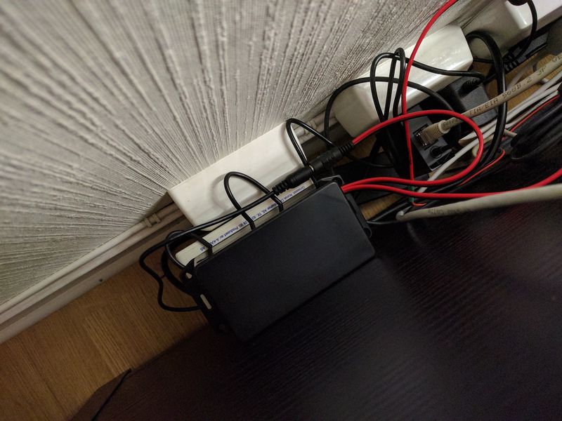 Plastic enclosure module, behind TV bench, power cables and AC adaptors