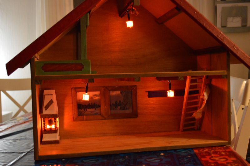 Miniature house with three lit lanterns suspended from ceiling