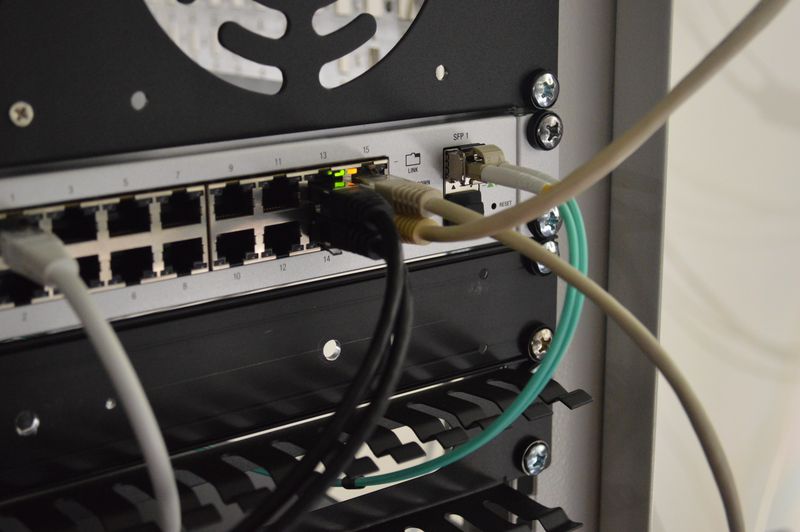 Network cables and fiber going into Unifi 16 port PoE switch mounted in rack