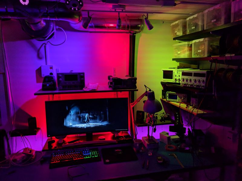 Computer desk with ultrawide monitor and electronics lab, lit by Philips Hue lamps