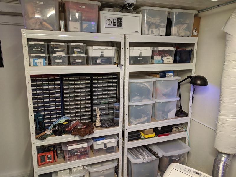 Two shelf units with clear plastic boxes and drawer cabinets for parts storage