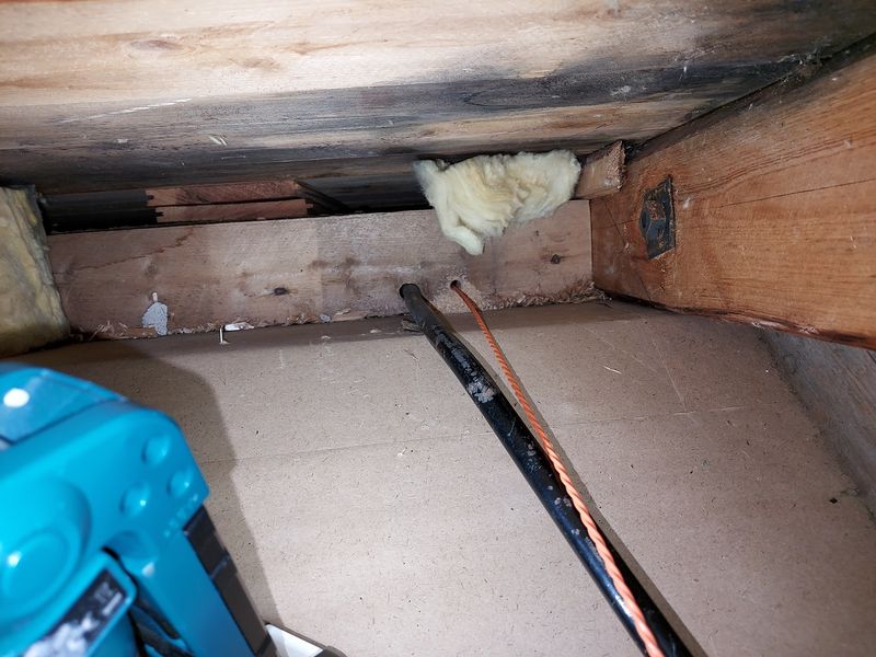 Fish tape in pilot hole in beam between rafters