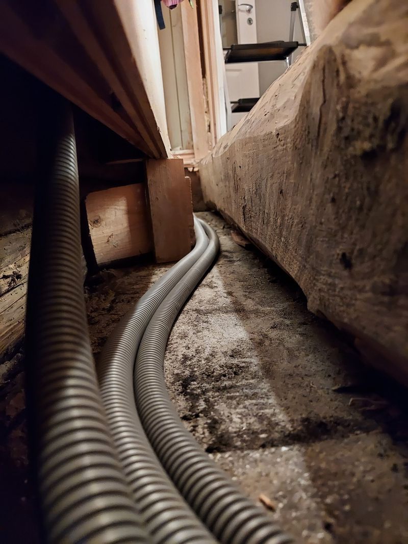 Flexible conduits in cavity around basement stairwell